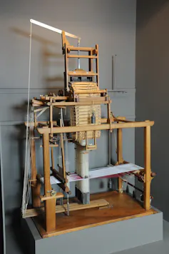 Un métier à tisser dans un musée. Au centre, on aperçoit les cartes perforées qui passent à travers la machine