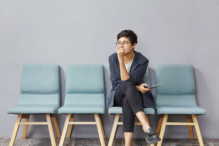 Woman sits on chair in row with her hand resting against her mouth