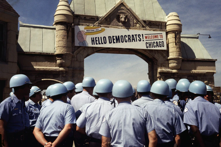A large number of police in helmets looks at a sign welcoming delegates to Chicago and the convention.