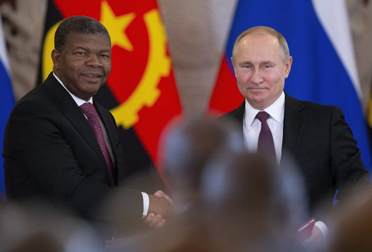 two men in suits shaking hands.