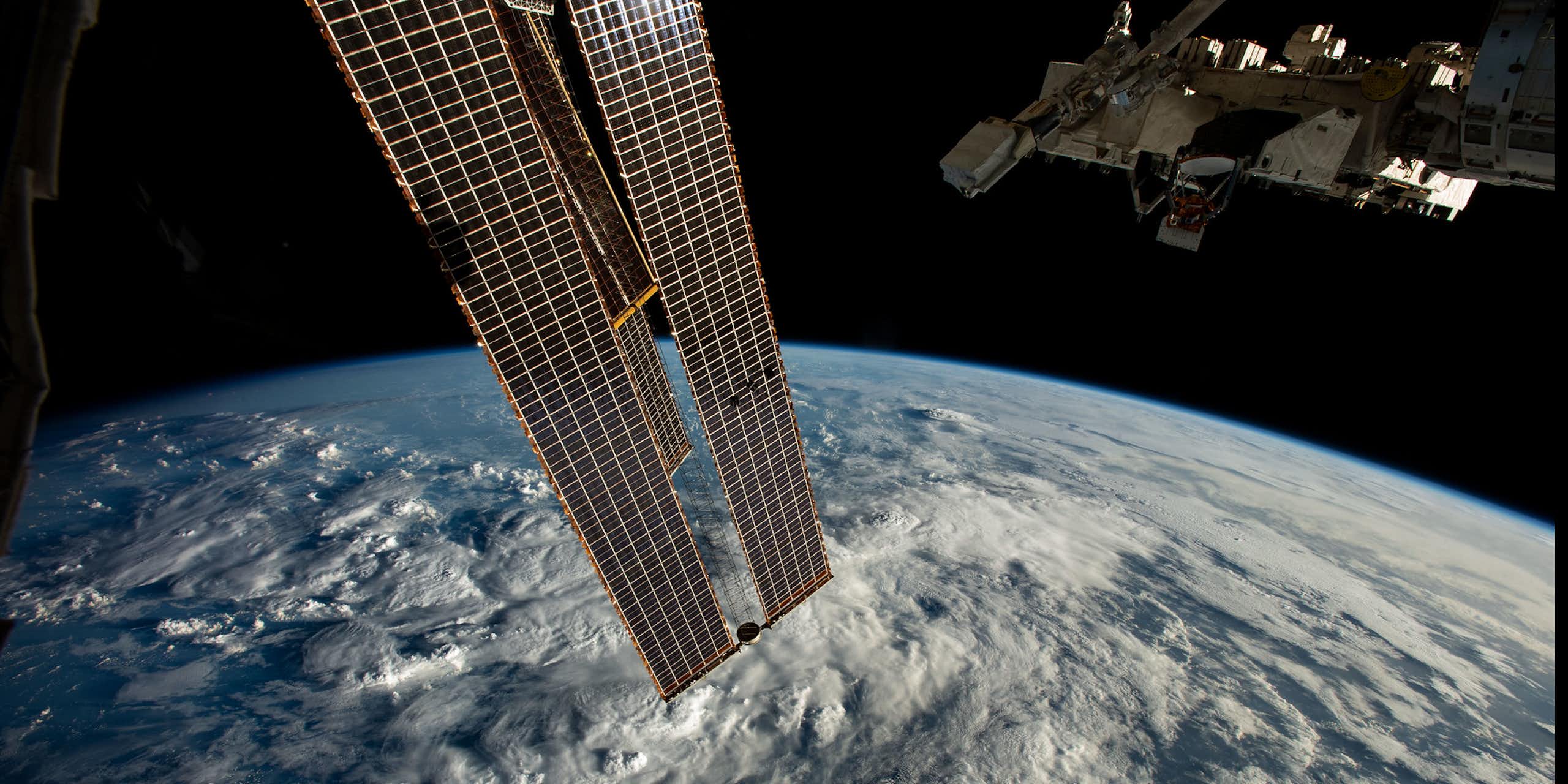 long thin rectangular structure in orbit above clouds on Earth