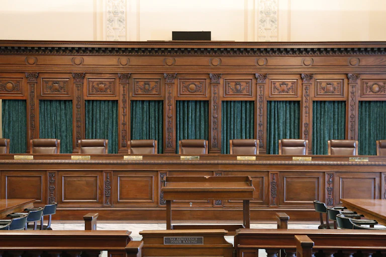 A formal, wooden dais with nine leather seats and dark green curtains.