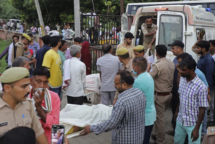 People loading victims into back of ambulance after deadly crowd crush in India
