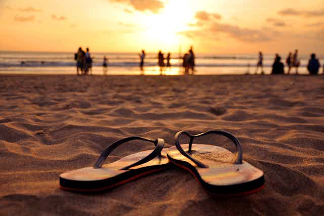 Flip flops on a beach at sunset.