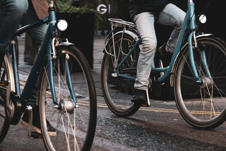 Two people ride bikes along a path.