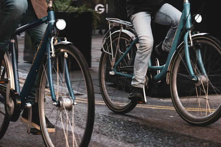 Two people ride bikes along a path.