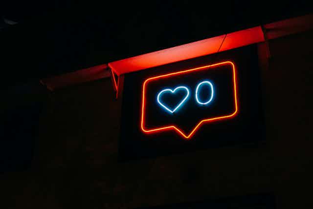 A neon sign of the like symbol, showing zero likes. 