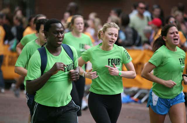 Un homme et deux femmes en train de courir en grimaçant.