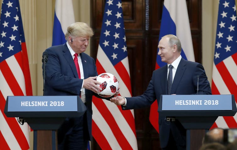 Donald Trump accepts a football from Vladimir Putin at their 2016 summit meeting in Helsinki.