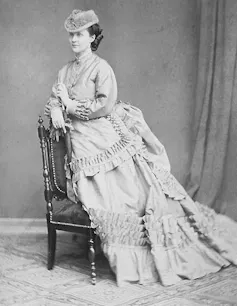 Young woman in Victorian clothing, a long dress and top hat.