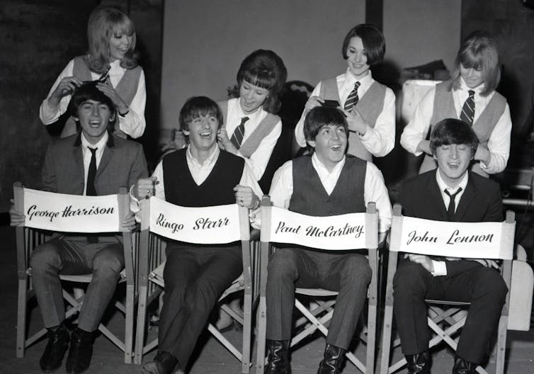 The Beatles in directors' chairs on a film set