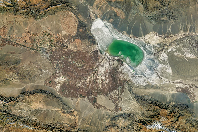 A shrinking saline lake seen from above, with the water occuping a small part of the dried-up lake bed