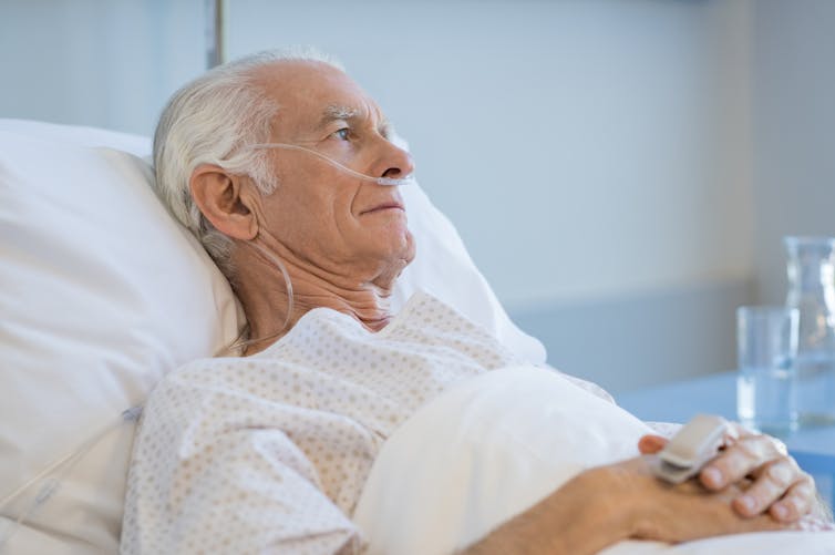 A senior man in a hospital bed.