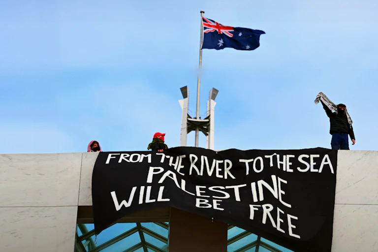 Pro-Palestine protesters hang banners from the top of Parliament House in Canberra, Thursday