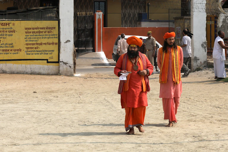 Two Hindu holy men dressed in orange robes arriving at a polling station.