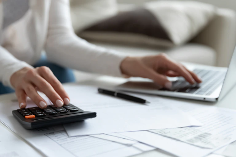 Woman using calculator and laptop