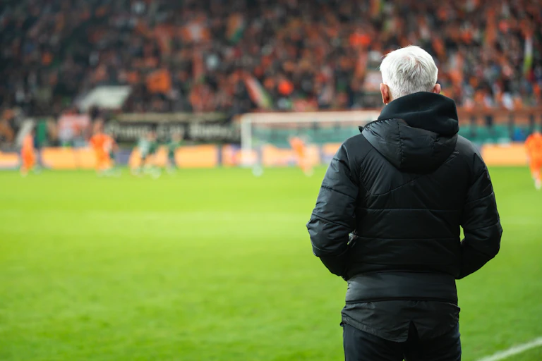 Un entraîneur de foot de dos dans un stade.