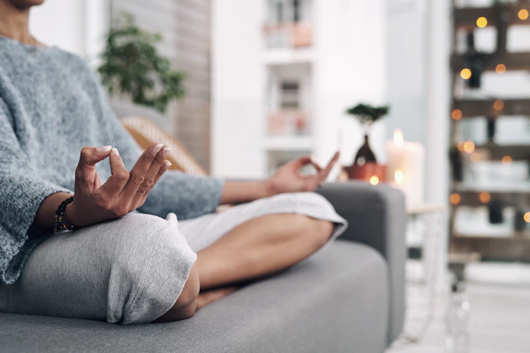 Woman sits on sofa meditating