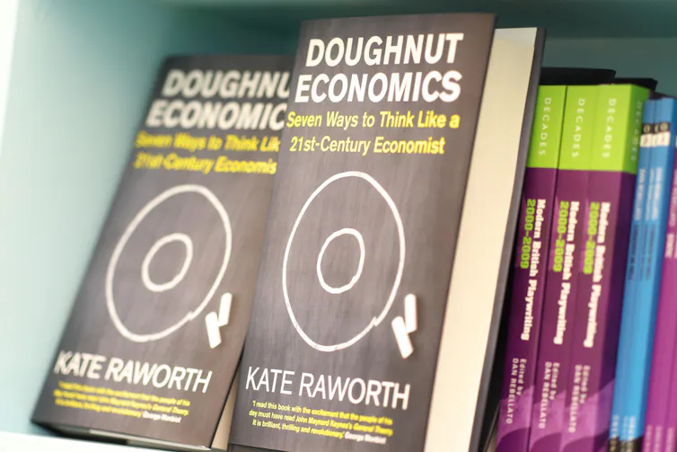 close up of black books on shelf, with title Doughnut Economics