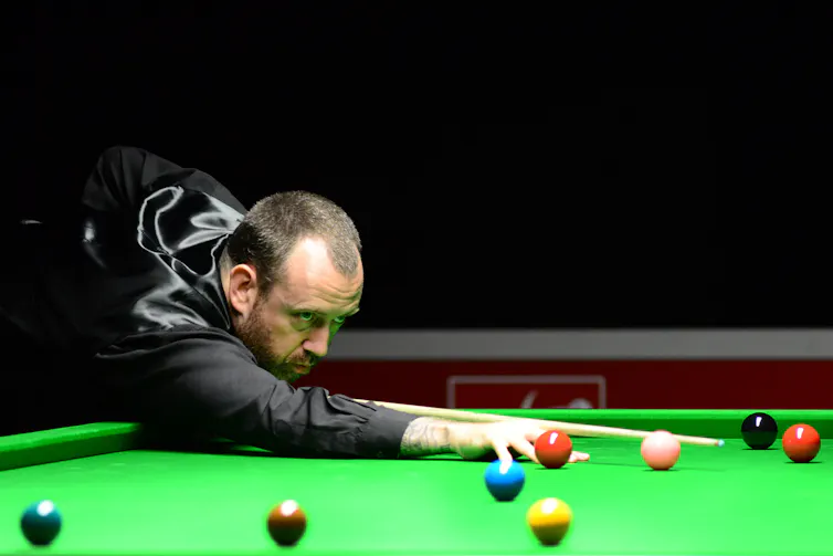 A snooker player, showing a sharp upwards gaze.