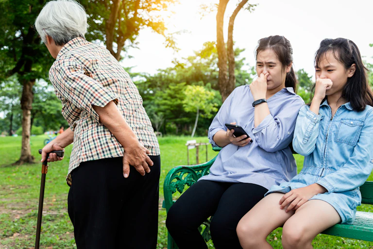 Older adult walking past two young women in a park