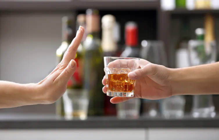 A person refusing a glass of alcohol