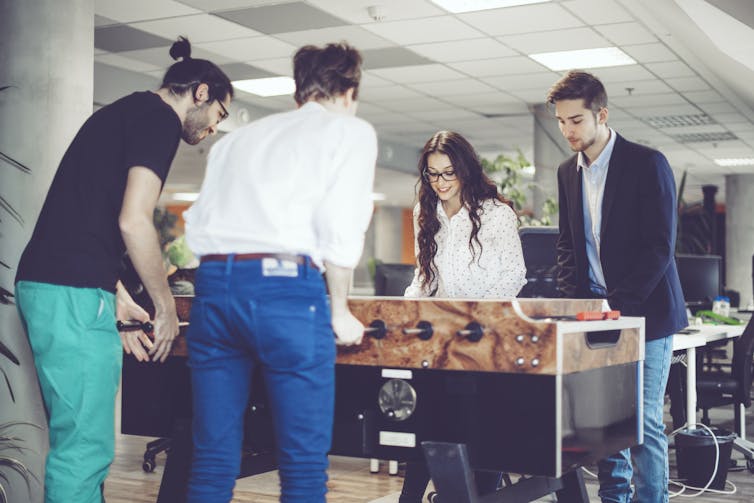 Young adults are relaxing by playing foosball together