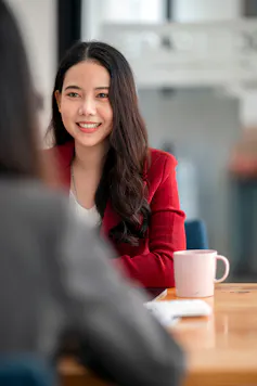 Woman seen smiling sitting across a table in a job interview
