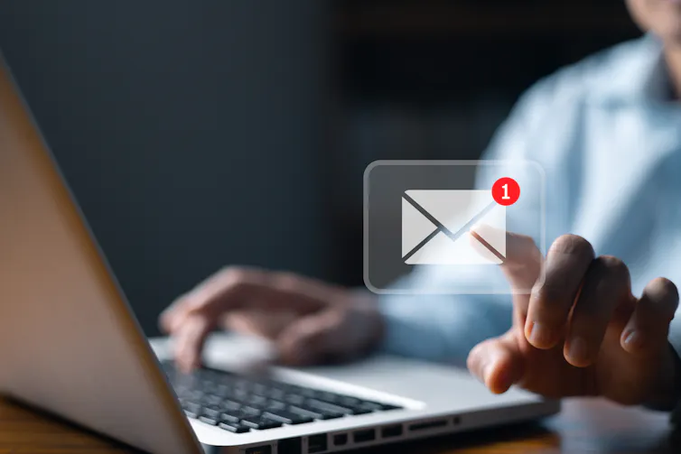 Man touches email icon floating above a laptop