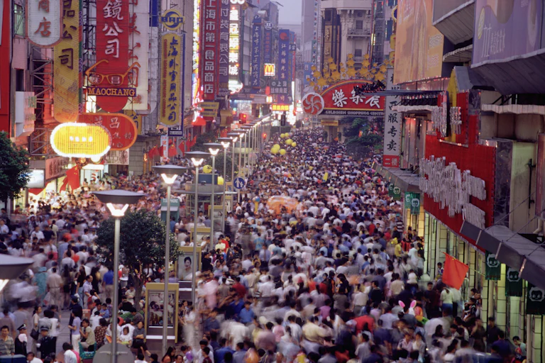A street crowded with people on foot, and Chinese language signage on buildings