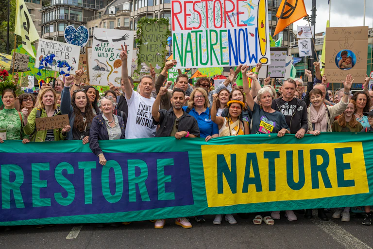 protestors in street and big colourful banners with words Restore Nature Now