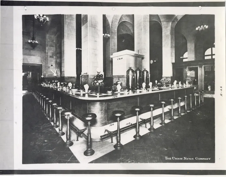 Black and white photo of a lunch counter in the Michigan Central Station Depot featuring stools and a bar.