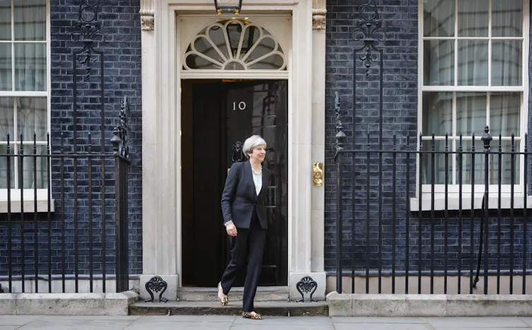 Former PM Theresa May walking out of Number 10 wearing a black pantsuit