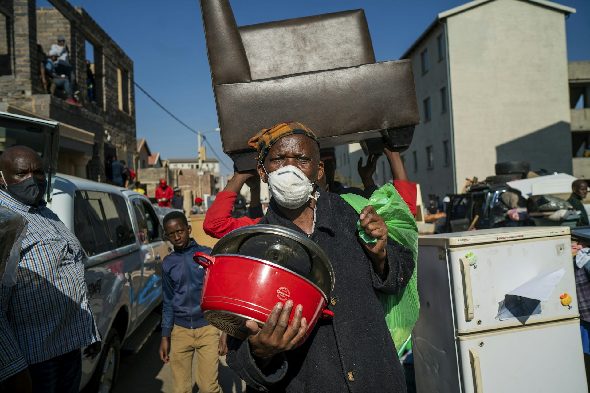 Des gens marchent dans la rue en transportant leurs biens.