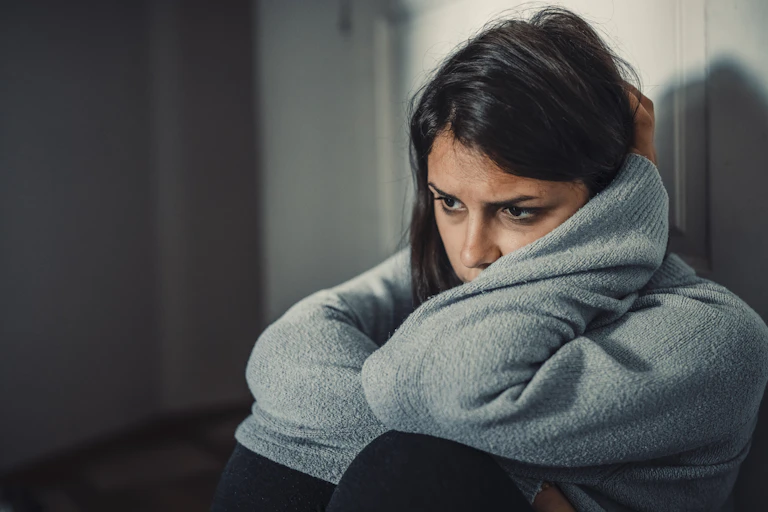 Woman wraps arms around self and looks depressed
