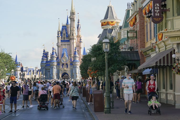 People walk down a street with at the disney world theme park