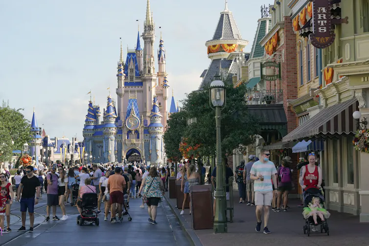 People walk down a street with at the disney world theme park