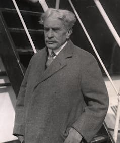 A black-and-white photo of a man with white hair and a moustache.