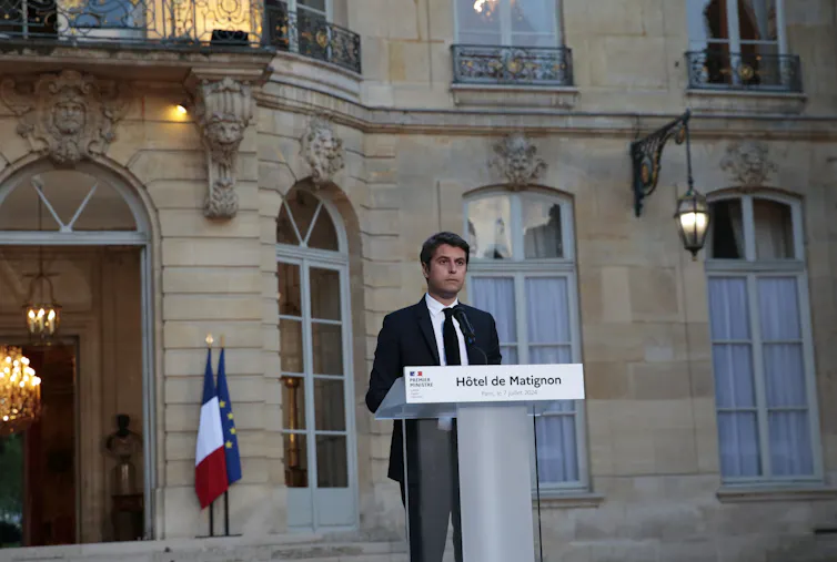 O primeiro-ministro da França, Gabriel Attal, fala em um pódio.