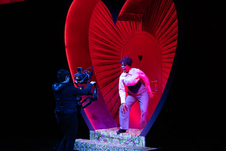 A actor on stage inside a giant heart.