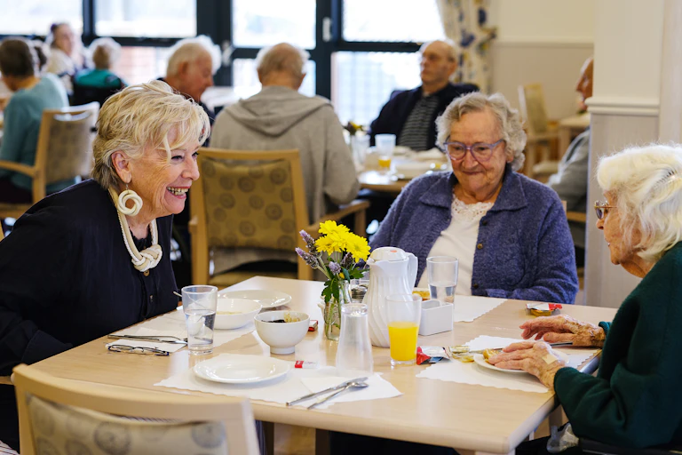 people sit talking and eating in an aged care setting