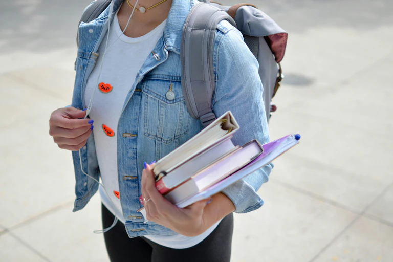 A uni student carries some books.
