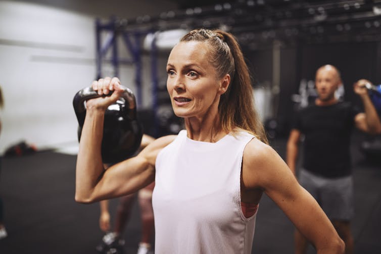 A woman lifting a weight in a gym.