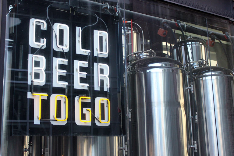 a sign reading COLD BEER TO GO with two metal cylinders