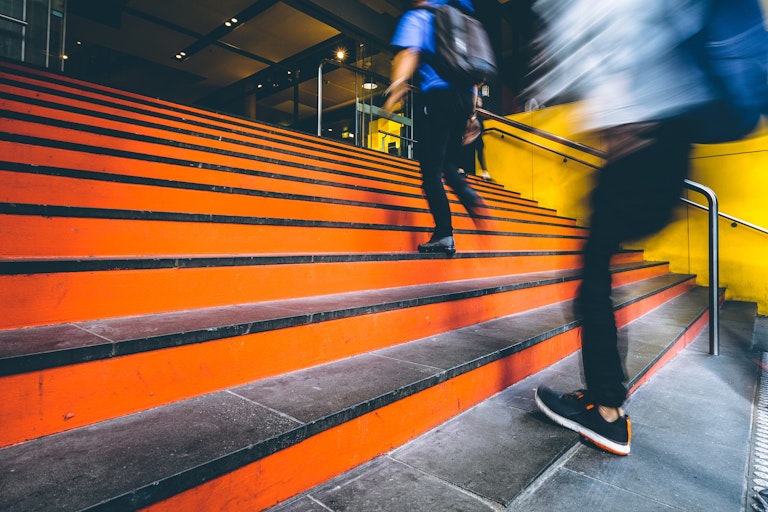 blurred motion people walking up an orange staircase