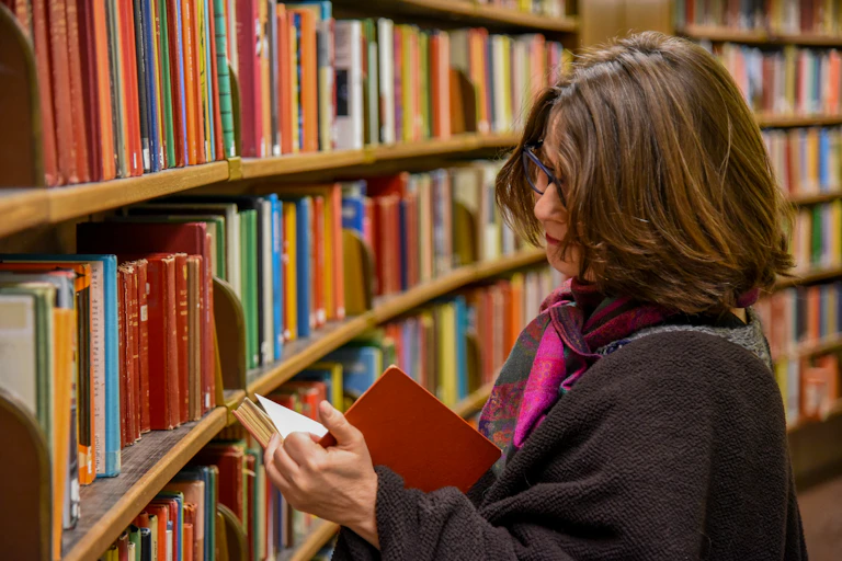 A woman reading a book in a library.