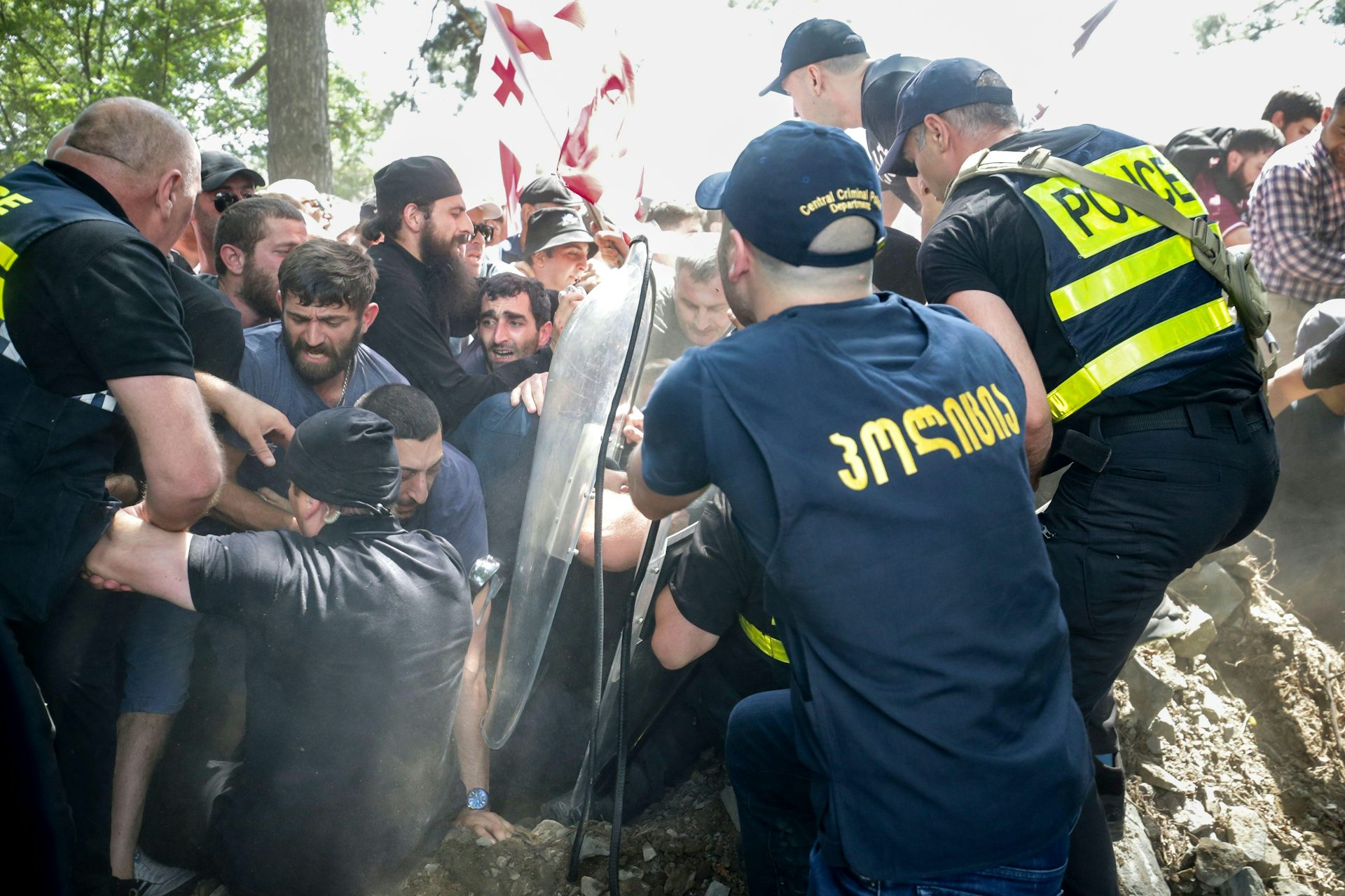 Georgian policemen struggling to hold back a crowd of anti-LGBT protestors.