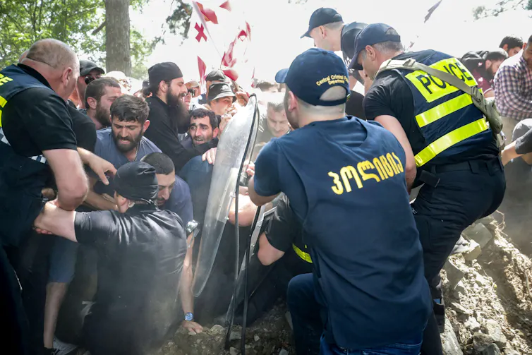 Georgian policemen struggling to hold back a crowd of anti-LGBT protestors.