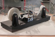 Reproduction d’une machine de Turing. Un long ruban, enroulé de chaque côté, passe sous la tête de lecture/écriture