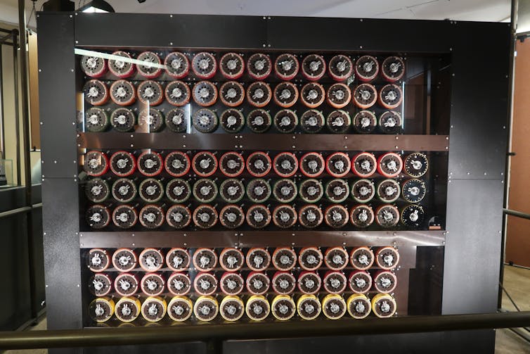 Dans une grande armoire vitrée, de nombreux rouleaux colorés sont visibles de profil